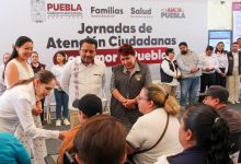 Personal médico de la Secretaría de Salud atiende a una mujer adulta mayor en una unidad móvil durante la jornada de salud en Tehuacán; de fondo se observa un banner del programa “Por Amor a Puebla”.