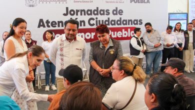 Personal médico de la Secretaría de Salud atiende a una mujer adulta mayor en una unidad móvil durante la jornada de salud en Tehuacán; de fondo se observa un banner del programa “Por Amor a Puebla”.