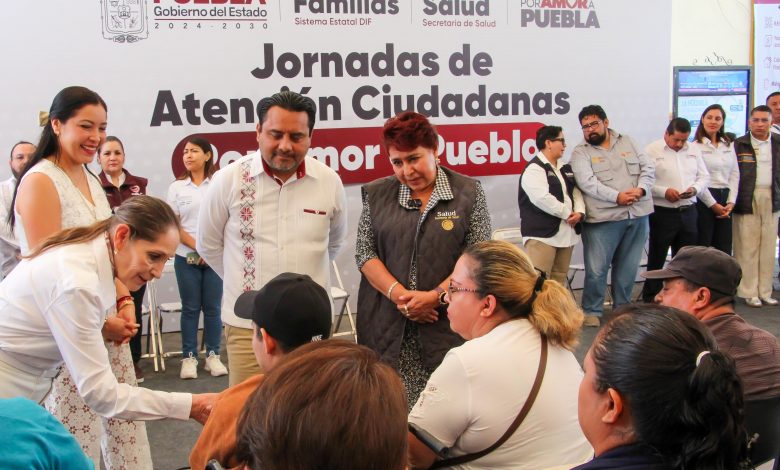 Personal médico de la Secretaría de Salud atiende a una mujer adulta mayor en una unidad móvil durante la jornada de salud en Tehuacán; de fondo se observa un banner del programa “Por Amor a Puebla”.