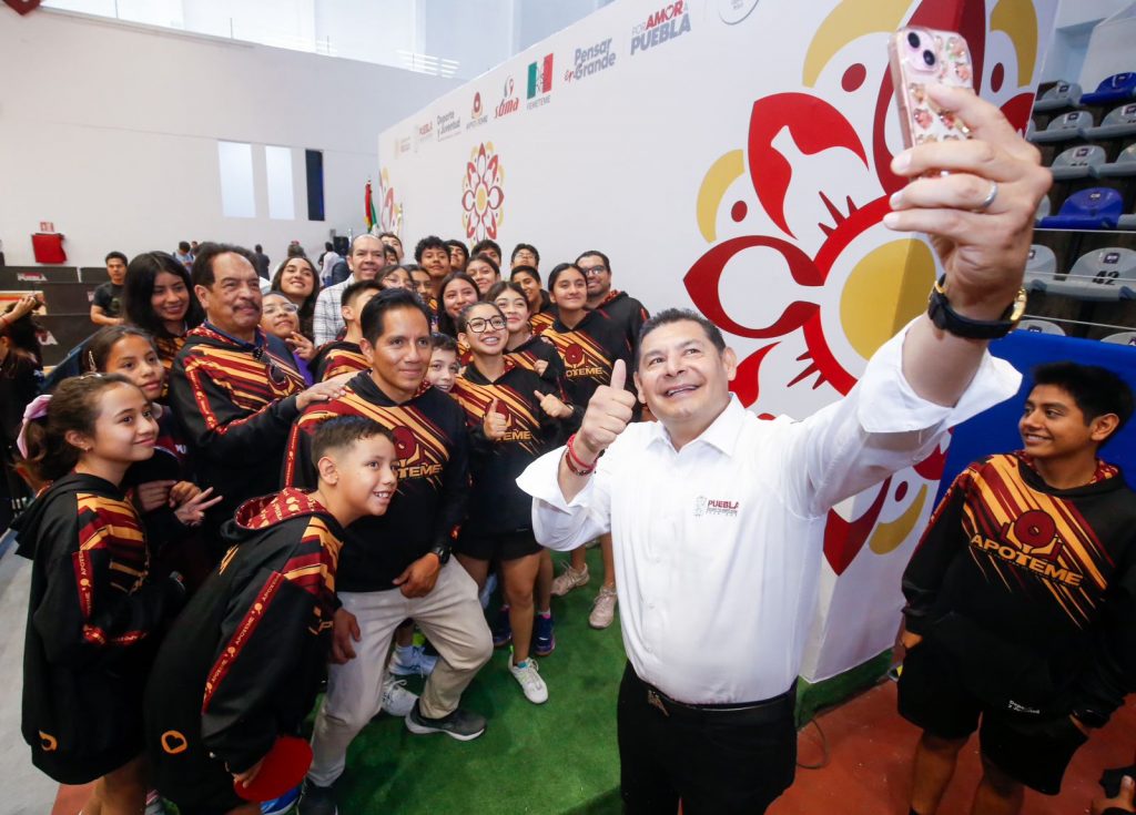 Un plano medio, tomado desde un ángulo elevado, muestra a Alejandro Armenta Mier, Gobernador de Puebla, tomándose una selfi con su teléfono móvil. 