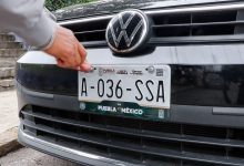 Manos ajustando con un destornillador una placa de matrícula oficial de transporte público en un vehículo.