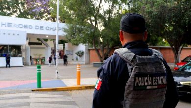 Oficial de la Policía Estatal de Puebla de espaldas, portando chaleco táctico, vigilando la entrada del Centro Escolar Niños Héroes de Chapultepec ante operativos por retos virales.