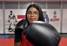 Fotografía de primer plano de la boxeadora Fátima Ramos de la BUAP, portando uniforme deportivo y con el guante de boxeo extendido hacia el frente en posición de guardia