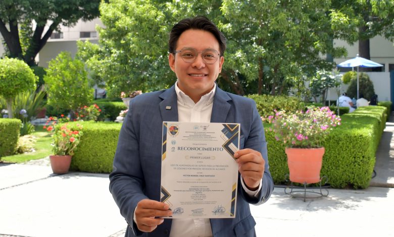 Víctor Manuel Cruz Santiago sostiene su reconocimiento de primer lugar en un jardín.