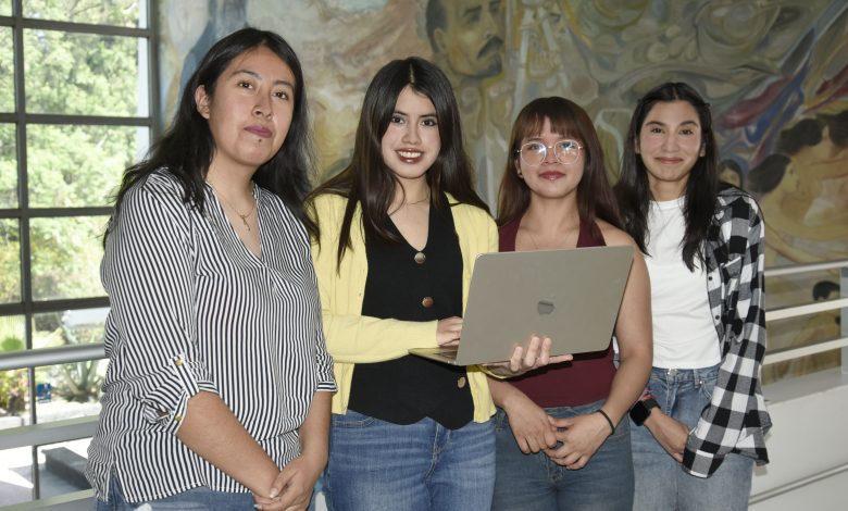 Cuatro estudiantes de la BUAP posan con una laptop frente a un mural en las instalaciones de la universidad