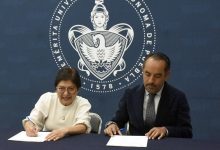 Rectora de la BUAP y director de Atención Estudiantil firman documentos en una mesa, con el escudo de la universidad de fondo.