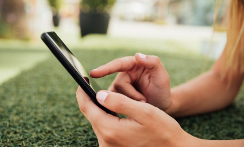 Joven usando smartphone al aire libre, imagen que ilustra el uso de redes sociales y el riesgo de ciberacoso
