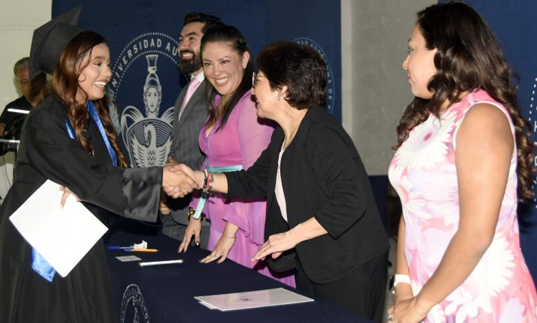 La rectora de la BUAP, Lilia Cedillo Ramírez, estrecha la mano de una egresada con toga y birrete durante la graduación de la Preparatoria de Izúcar de Matamoros.