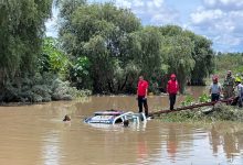 Patrulla de la Policía Municipal semihundida en el río Atoyac durante las maniobras de rescate en Ocoyucan; un buzo se sumerge junto a la unidad mientras elementos de rescate y militares trabajan desde la orilla.